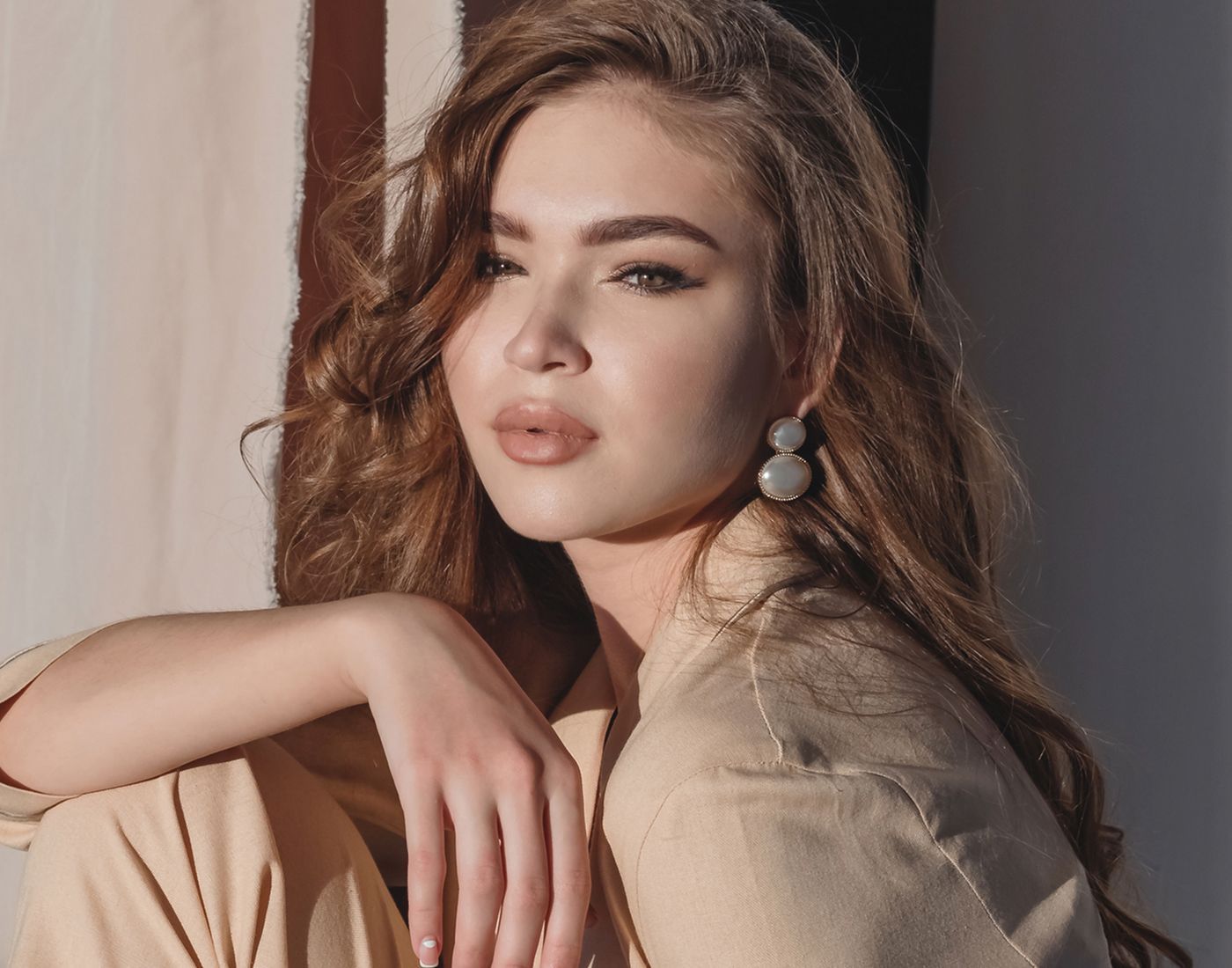 Stylish young woman with curly hair and earrings.